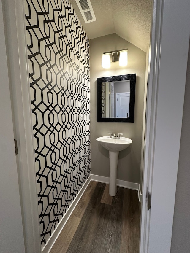 bathroom with wood-type flooring, a textured ceiling, and lofted ceiling