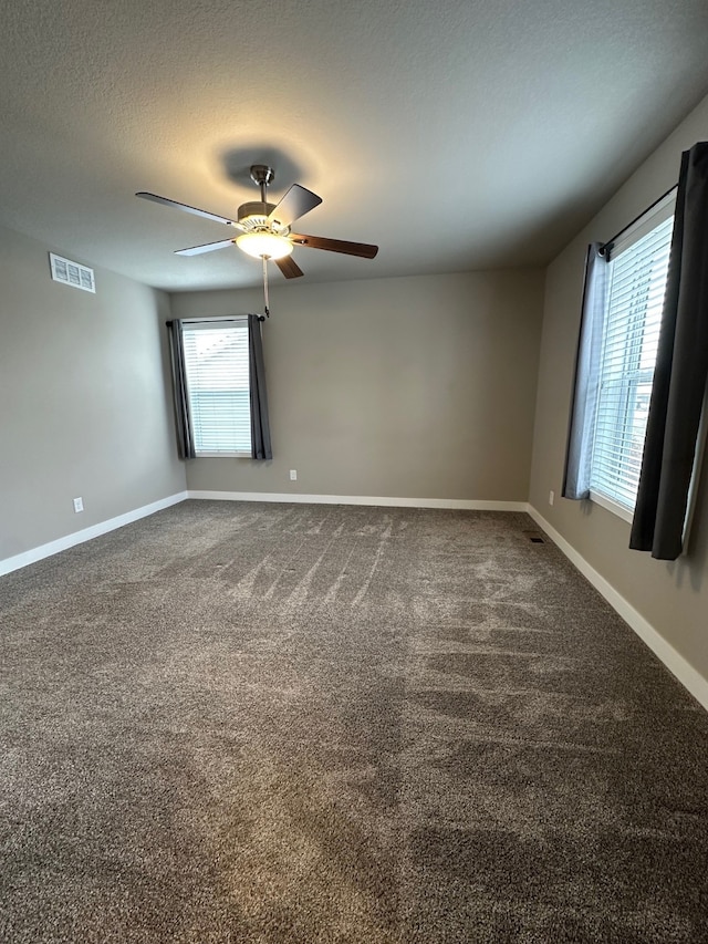 empty room featuring ceiling fan, carpet, a textured ceiling, and a healthy amount of sunlight