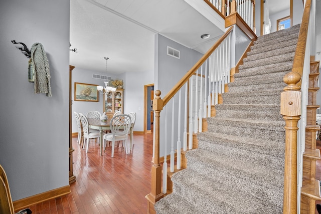 staircase featuring a chandelier and hardwood / wood-style floors