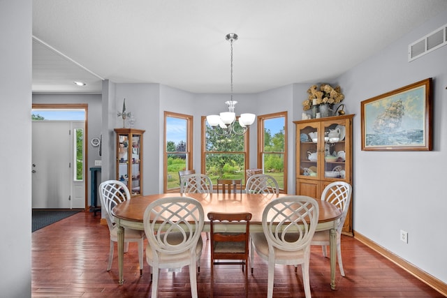 dining area with dark hardwood / wood-style floors and a notable chandelier