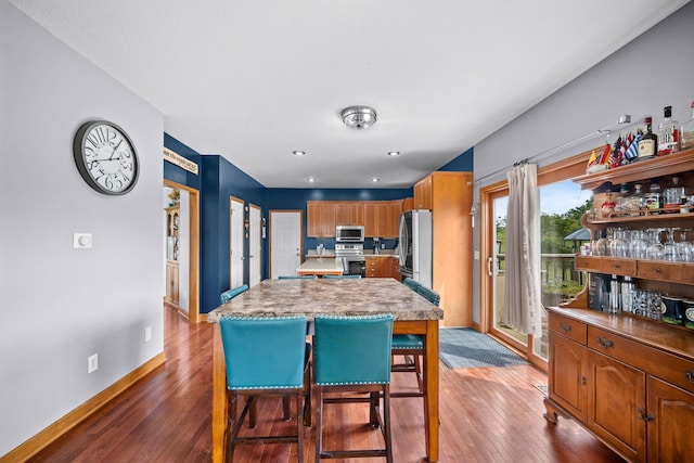 kitchen featuring a center island, hardwood / wood-style floors, appliances with stainless steel finishes, and a kitchen breakfast bar