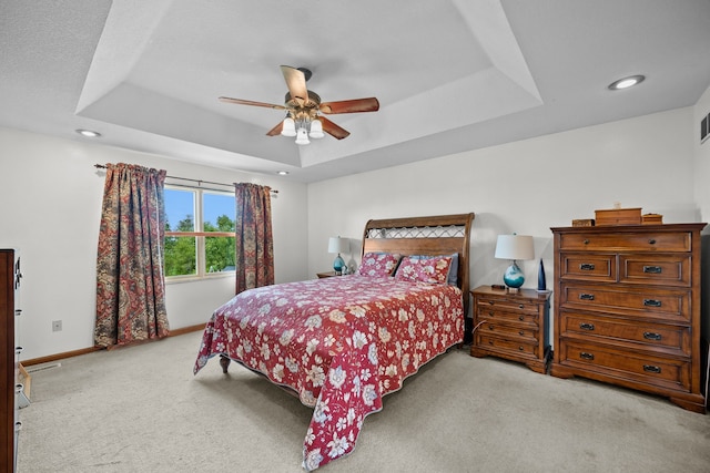 bedroom featuring light colored carpet, ceiling fan, and a raised ceiling