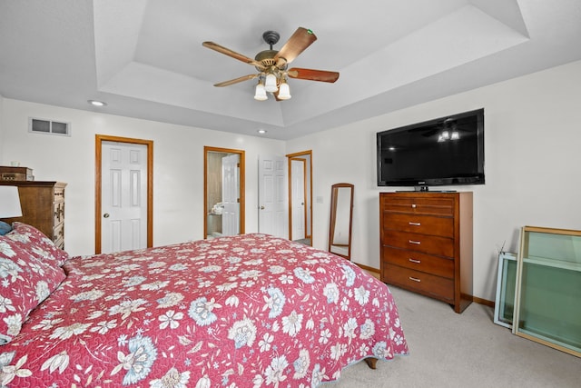 carpeted bedroom with ceiling fan and a tray ceiling