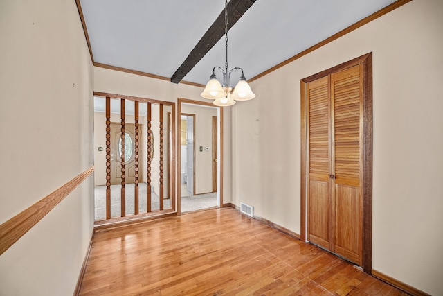 unfurnished dining area with crown molding, light hardwood / wood-style floors, and an inviting chandelier