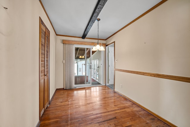 unfurnished dining area featuring hardwood / wood-style flooring, beamed ceiling, crown molding, and a chandelier