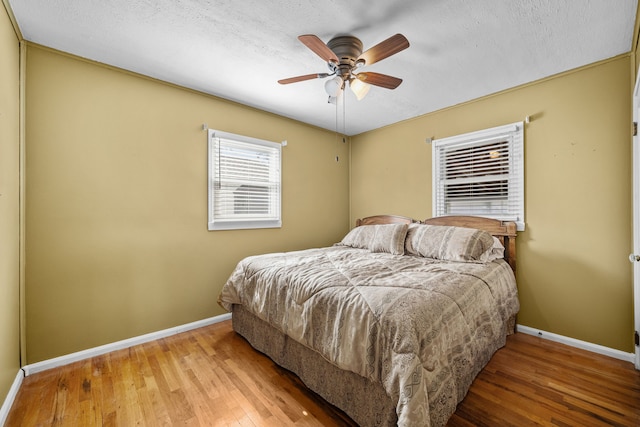 bedroom featuring ceiling fan, hardwood / wood-style floors, and a textured ceiling