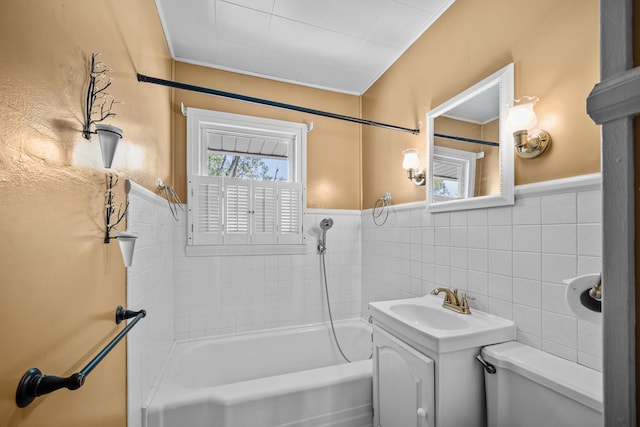 full bathroom featuring tiled shower / bath combo, toilet, vanity, and tile walls