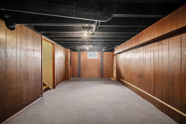 basement with carpet and wood walls