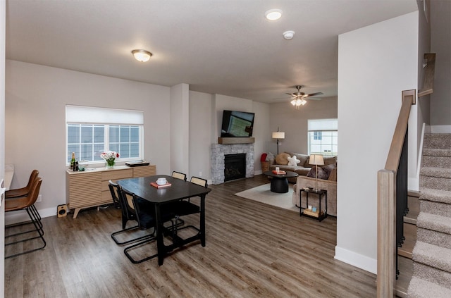 living room with ceiling fan, dark hardwood / wood-style flooring, and a stone fireplace