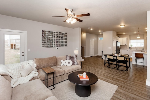 living room featuring dark hardwood / wood-style flooring, ceiling fan, and sink