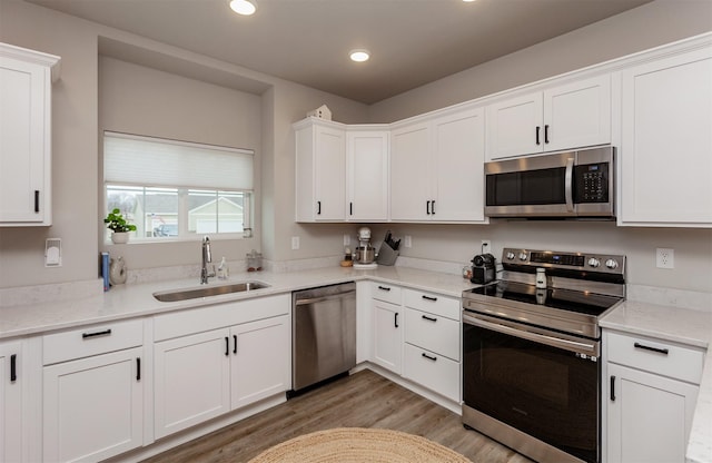 kitchen with white cabinetry, sink, stainless steel appliances, and light stone counters