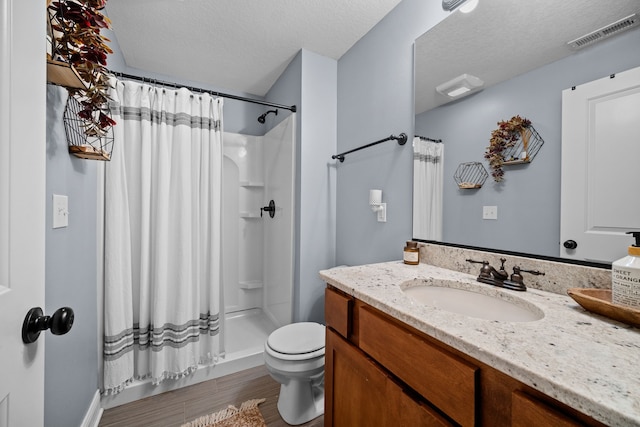 bathroom with wood-type flooring, curtained shower, a textured ceiling, toilet, and vanity