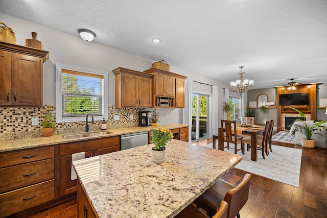 kitchen with dishwasher, a kitchen breakfast bar, sink, a kitchen island, and pendant lighting