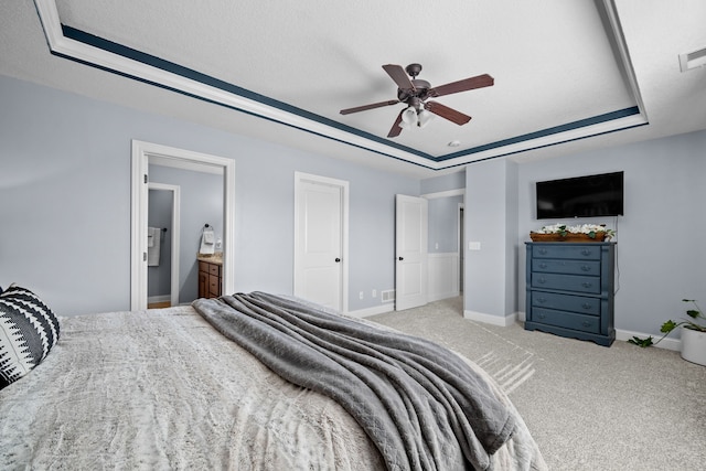 carpeted bedroom with ceiling fan, connected bathroom, a raised ceiling, and a textured ceiling