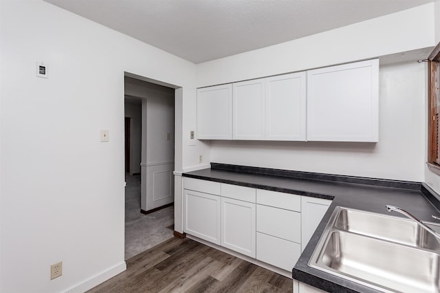 kitchen with dark wood-type flooring, sink, and white cabinetry