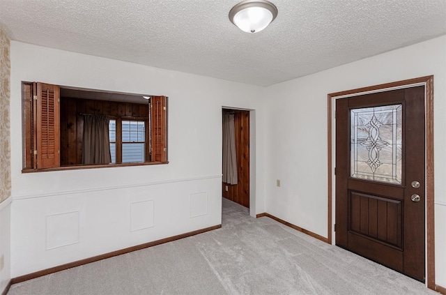 carpeted foyer entrance featuring a textured ceiling