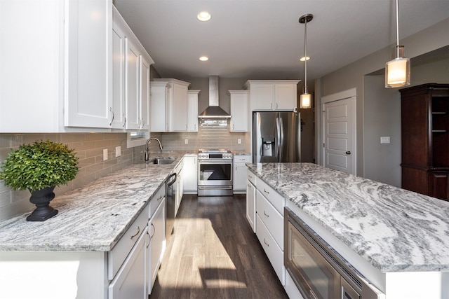 kitchen with wall chimney exhaust hood, white cabinets, a center island, and stainless steel appliances