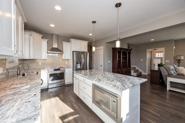 kitchen featuring a center island, appliances with stainless steel finishes, white cabinets, sink, and wall chimney exhaust hood