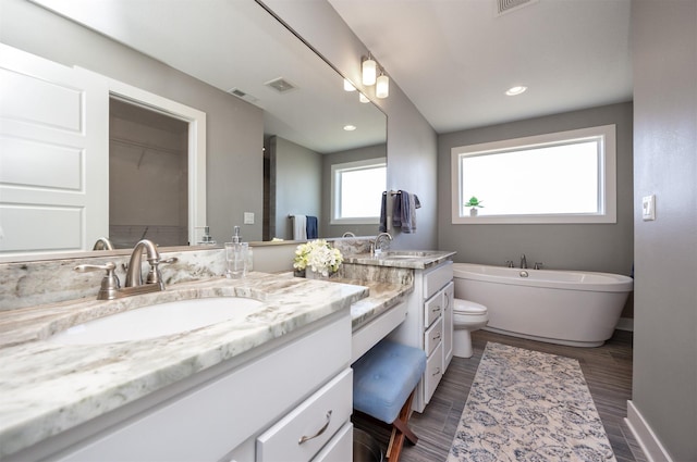 bathroom featuring a washtub, toilet, and vanity