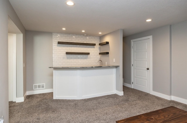 kitchen with carpet floors, sink, white cabinets, and stone counters