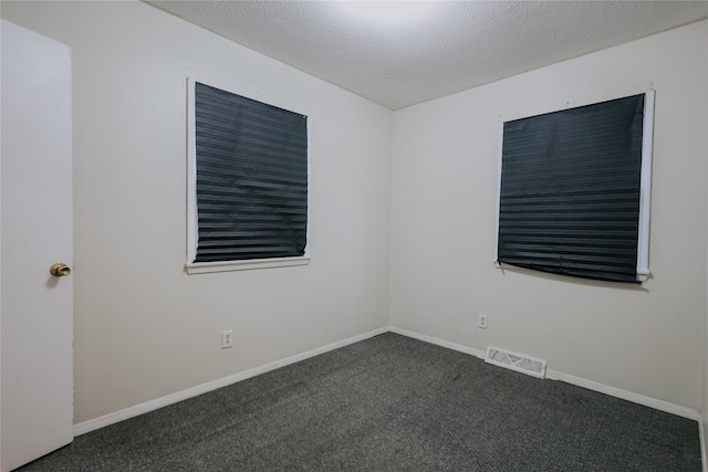 unfurnished room featuring dark colored carpet and a textured ceiling