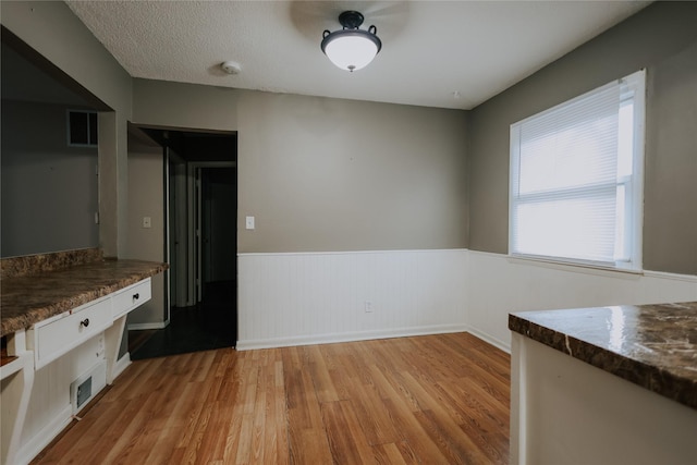 unfurnished dining area with light hardwood / wood-style floors and a textured ceiling