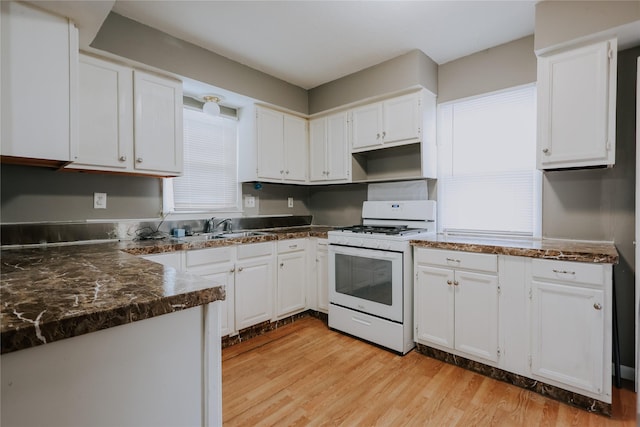 kitchen with white range with gas stovetop, sink, white cabinetry, and light hardwood / wood-style flooring