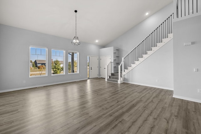 unfurnished living room featuring high vaulted ceiling, dark hardwood / wood-style flooring, and a chandelier