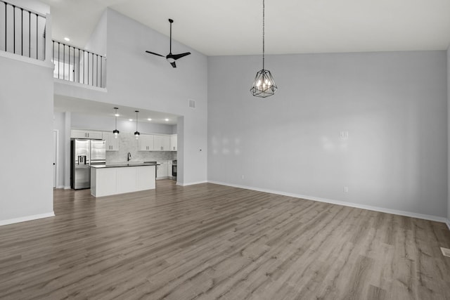 unfurnished living room featuring light wood-type flooring, a chandelier, and a towering ceiling