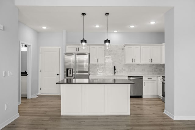 kitchen with tasteful backsplash, white cabinets, sink, pendant lighting, and stainless steel appliances