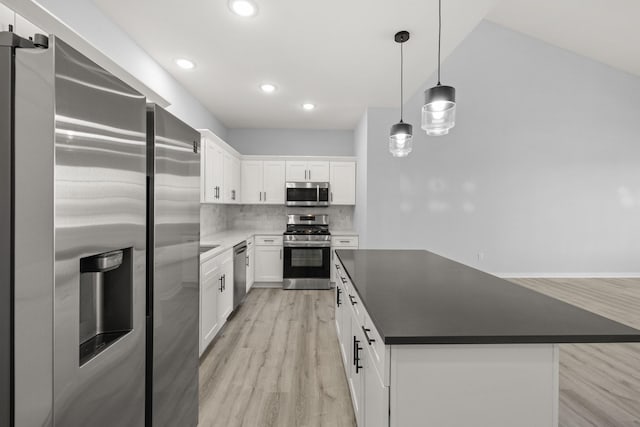 kitchen featuring decorative light fixtures, backsplash, white cabinetry, a kitchen island, and stainless steel appliances