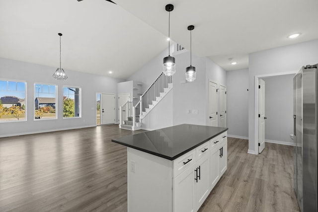 kitchen featuring lofted ceiling, decorative light fixtures, stainless steel refrigerator with ice dispenser, white cabinetry, and light hardwood / wood-style flooring