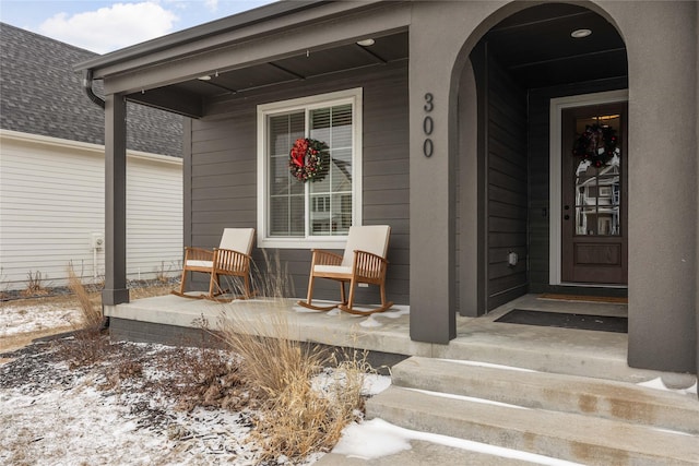 snow covered property entrance featuring covered porch