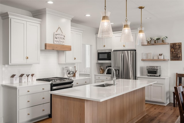 kitchen featuring white cabinets, an island with sink, appliances with stainless steel finishes, and sink