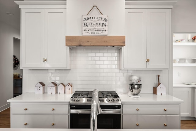 kitchen with premium range hood, white cabinetry, decorative backsplash, and stainless steel gas range