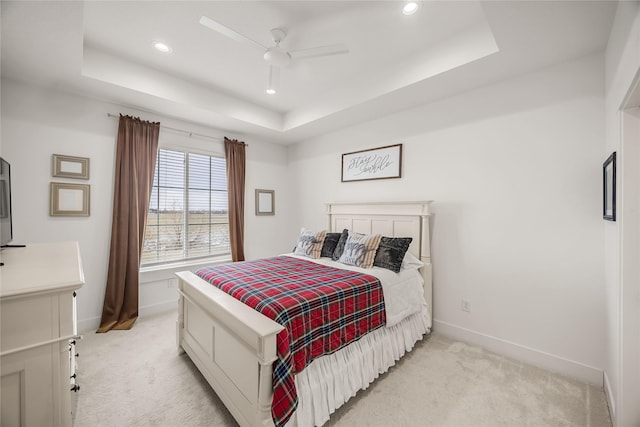 bedroom featuring ceiling fan, light carpet, and a raised ceiling