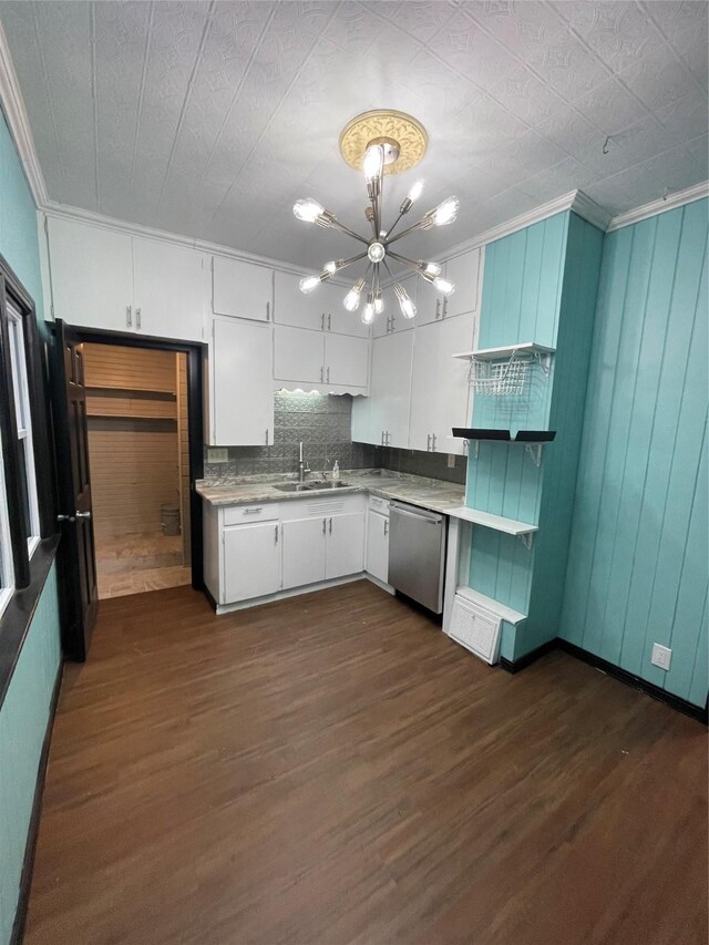 kitchen with dishwasher, sink, white cabinetry, ornamental molding, and an inviting chandelier