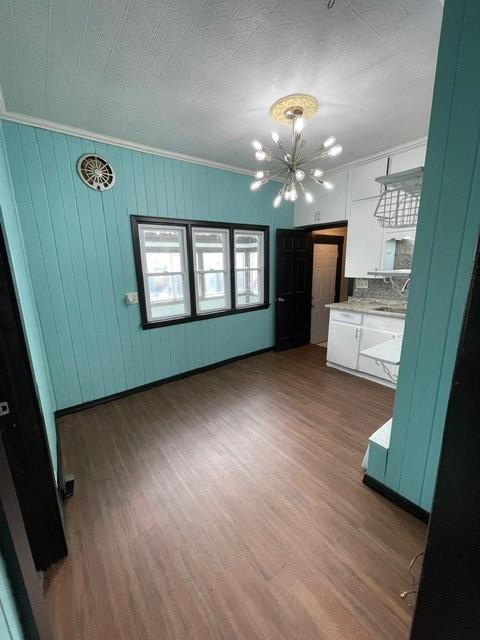 interior space featuring dark hardwood / wood-style flooring, ornamental molding, and a notable chandelier