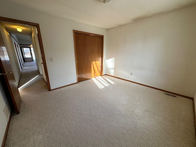 unfurnished bedroom with a textured ceiling, carpet floors, and a closet