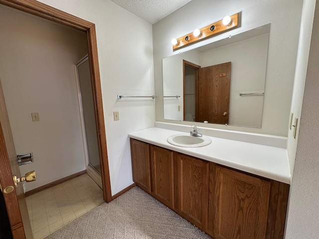 bathroom featuring vanity, walk in shower, and a textured ceiling