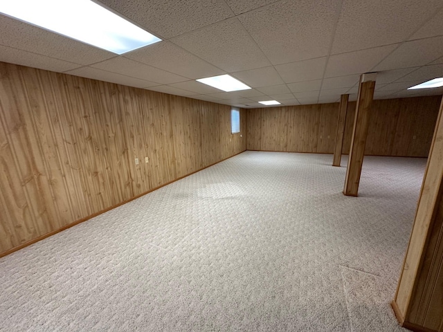 basement featuring a paneled ceiling and light carpet