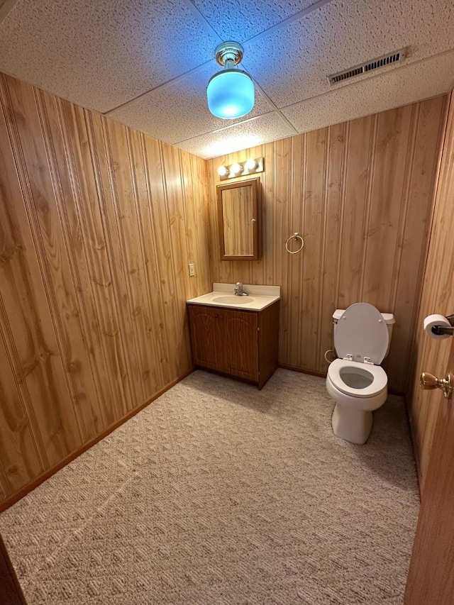 bathroom with toilet, vanity, and wooden walls