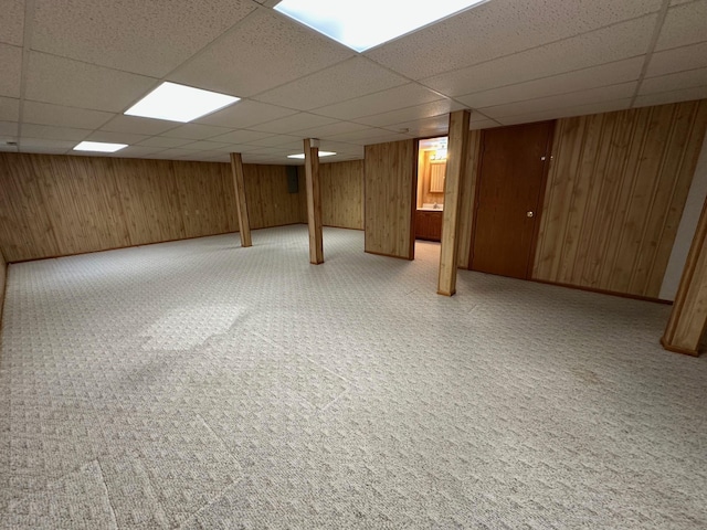 basement with wooden walls and a drop ceiling