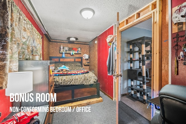 carpeted bedroom with wood walls and a textured ceiling