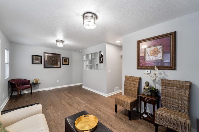 living area featuring built in features, hardwood / wood-style floors, and a textured ceiling