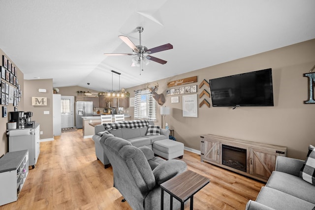 living room featuring vaulted ceiling, ceiling fan, and light hardwood / wood-style floors