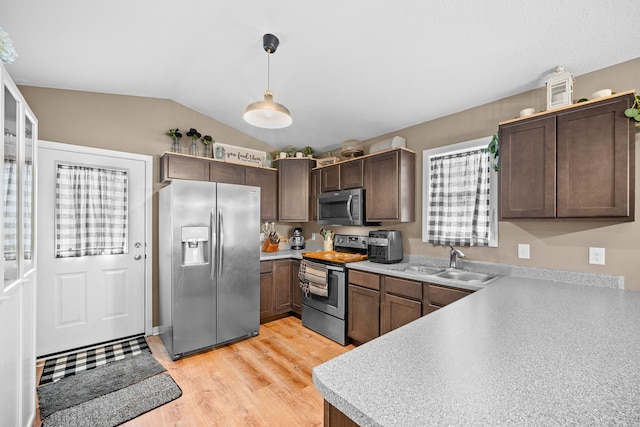 kitchen with dark brown cabinets, pendant lighting, appliances with stainless steel finishes, sink, and light hardwood / wood-style floors