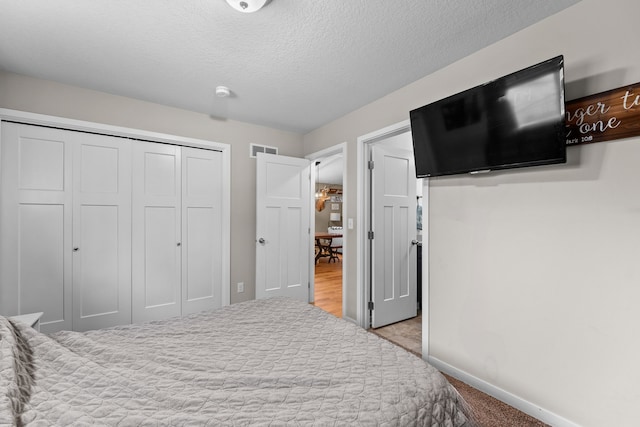 carpeted bedroom featuring a closet and a textured ceiling