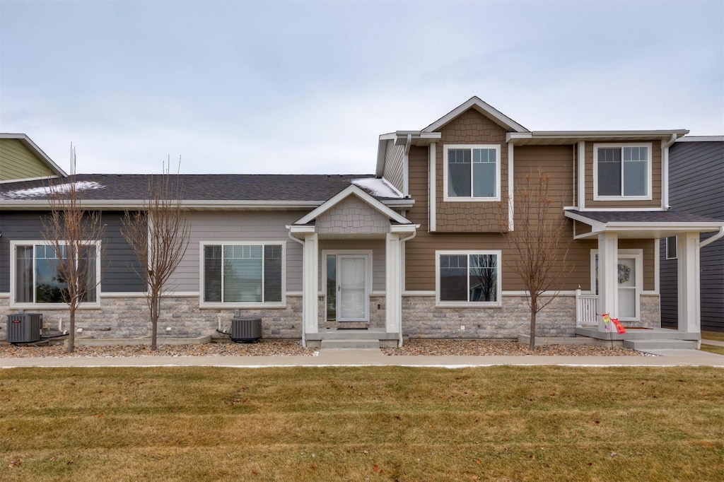 craftsman inspired home with a front lawn and central air condition unit