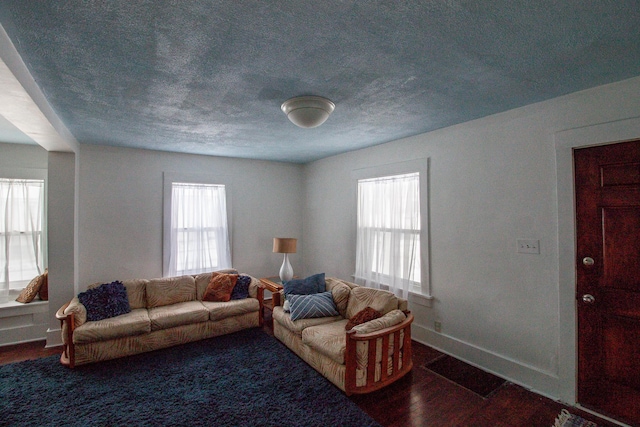 living room featuring dark wood-type flooring and a textured ceiling